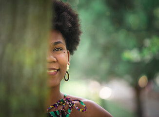 creative spring portrait. face of a girl hiding behind a tree trunk.