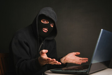 A dangerous masked hacker with a hood cannot infiltrate the data servers and infect them with viruses. Caught the criminal through a laptop.