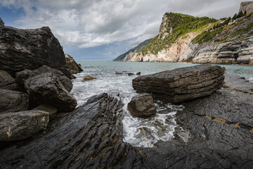 Beautiful seascape. Stormy sea on a windy day: blue waves breaks on the stone shore of Porto Venere...