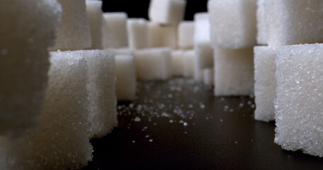 Refined sugar pyramid on the black table. Designing with light and shadow. Concept of sugar overuse. Unhealthy food. High quality photo.