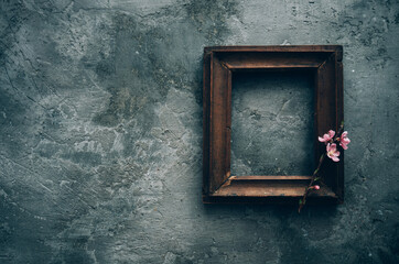 Vintage old wooden frame with spring flowers and leaves on dark rustic wooden background. Spring flowers composition with copy space.