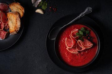 Bowl of tomato soup with deli meat directly above