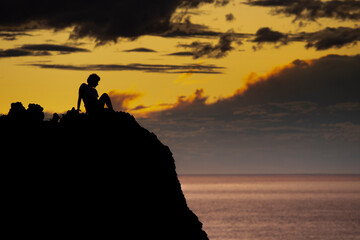 silhouette of people on the beach cliff at sunset