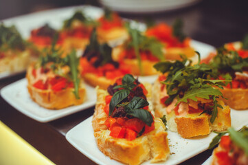 bruschetta with shrimps, basil, pesto and mozzarella sauce and tomato on a white plate on a wooden background. Italian restaurant. close-up of food