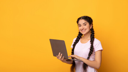 Naklejka premium Confident young indian woman holding and using laptop