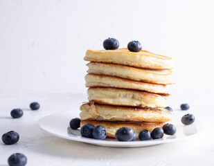 A stack of pancakes is on the plate. Blueberry berries are on the pancakes