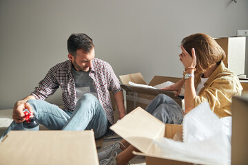 Couple searching for something among open cardboard boxes