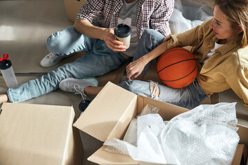 Fototapeta premium Two young people sitting on the floor among carton boxes