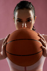 Attractive young woman holding orange basketball ball