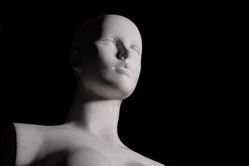 A white female manikin in low angle shot with black backgound. Arts, anotomy and photograhpy concept