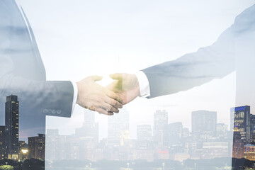 Double exposure handshake of two businessmen on office buildings background, collaboration and...