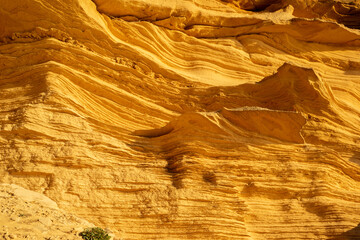 A sedimentary sandstone formation with vibrating yellow and orange colors  on a warm sunny day in the isalnd of Mallorca Spain