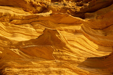 A sedimentary sandstone formation with vibrating yellow and orange colors  on a warm sunny day in the isalnd of Mallorca Spain