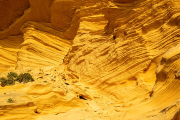 A sedimentary sandstone formation with vibrating yellow and orange colors  on a warm sunny day in the isalnd of Mallorca Spain