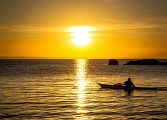 Naklejka na ściany i meble Sunset at Mallorca beach spain with a canoe kayak in the distance with the soft light of the evening sun during the golden hour