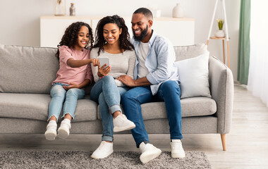 Happy african american family holding and using smartphone