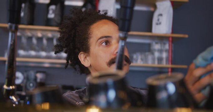 Mixed race male barista with moustache preparing takeaway coffee