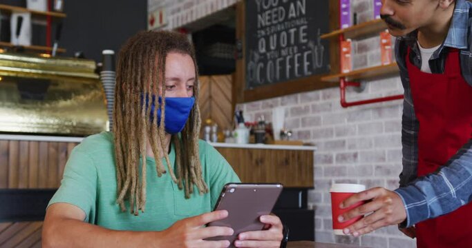 Mixed race male barista with dreadlocks serving coffee to customer