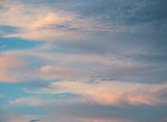 Pretty sunrise sky nature photo with clouds with pink and golden tones in blue sky.