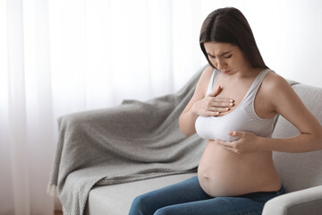 Millennial pregnant lady having painful feelings in breast area, suffering discomfort