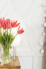A bouquet of tender pink tulips in a vase stand on the table. Beautiful spring bouquet. Gift for a woman, Comfort at home.