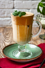 A glass of coffee with milk decorated with mint leaves, dalgon coffee