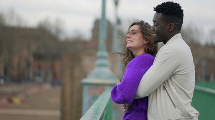  Happy millennial interracial couple standing outside laughing and smiling
