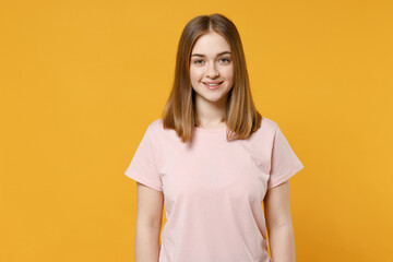Obraz premium Young smiling friendly happy positive caucasian european student woman 20s with nude make up wearing casual basic pastel pink t-shirt looking camera isolated on yellow background studio portrait