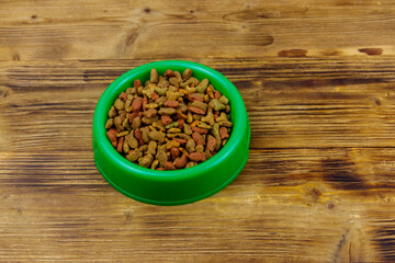 Dry food for cat or dog in bowl on wooden background. Pet food on wood surface