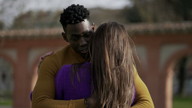Interracial couple empathic embrace. Young woman romantic connection with partner outside