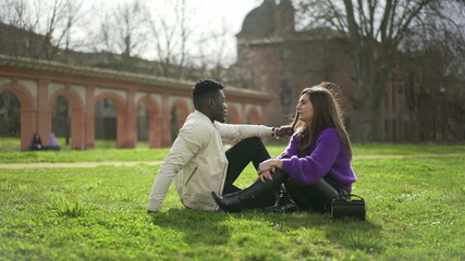  Interracial couple hanging together outside sitting on grass at park