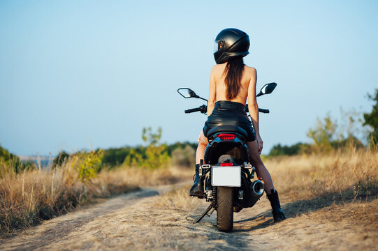girl biker without underwear in a helmet sitting on a black motorcycle