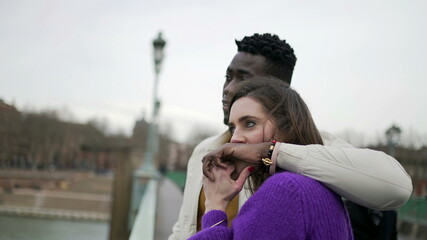 Interracial couple together, boyfriend arms around girlfriend, candid love and affection, kissing hand