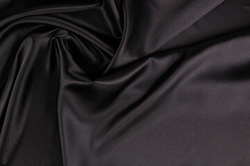 Beautiful elegant black background with drapery and wavy folds of silk satin material texture. Top...