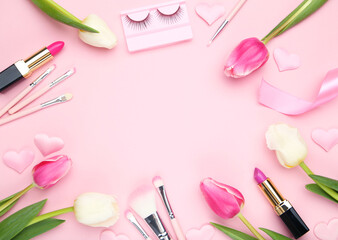 Obraz na płótnie Canvas Tulip flowers, makeup brushes, lipsticks and eyelashes on pink background