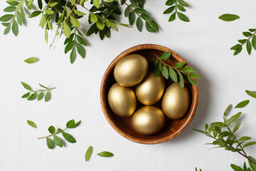 Easter concept with gold eggs and branch with green leaf on white background