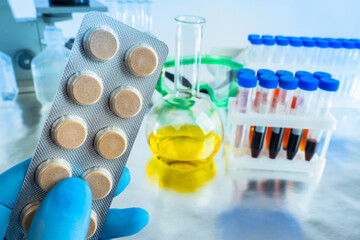 Pharmacological concept. Pills in the hands of a lab assistant. Pills on the background of the laboratory. Medicines testing in the laboratory. Development of medicines. Medical treatment of diseases