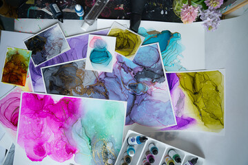 Table clutter in a creative studio. Alcohol Ink Painting. Above shot - 417926563