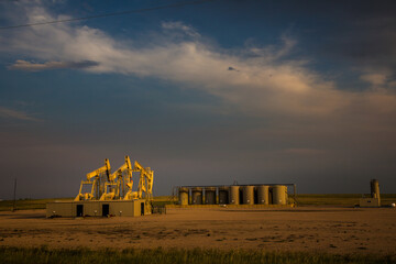 Ramer, Colorado, Working oil well pumps and storage tanks, near sunset,  along highway 14 near...