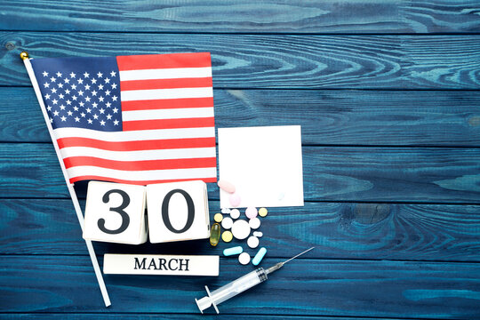 Text Happy Doctor's Day with cube calendar, american flag and colorful pills on blue wooden table