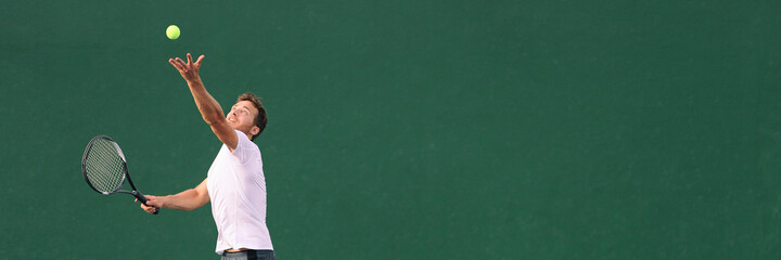 Tennis serve during match. Man tennis player playing throwing ball in the air serving playing on hard indoor court panoramic banner. - obrazy, fototapety, plakaty