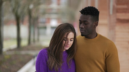 Young interracial couple kissing holding hands walking outside together