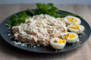Breakfast on a plate oatmeal, egg and greens close-up.