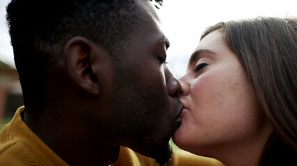 Young interracial couple kiss. Millennial lovers, African and white couple