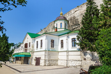 Fototapeta na wymiar Trinity Church in Inkerman cave monastery complex. It was built in 1850 nearby site of ancient Byzantine church (founded in 8 AD). Caves in rocks behind used as monk cells. Shot in Inkerman, Crimea