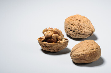 Three large walnuts in the shell and the kernel of one nut on a gray background