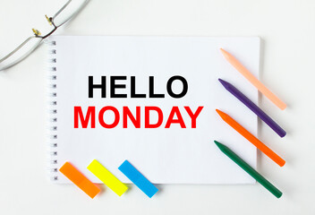 Notepad with text Hello Monday glasses colored pencils and colored stickers