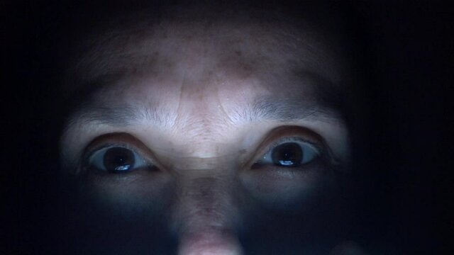 4K Lightened by screen a woman face watching news in the darkness
