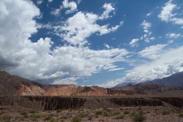 High in the cordillera. Panorama view of the orange rocky cliffs, precipice and colorful mountains under a blue sky.