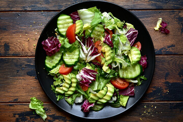 Fresh delicious vegetable salad with avocado, tomato, cucumber. Top view with copy space.